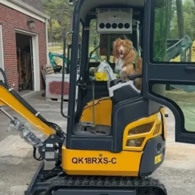 Woman operating a small excavator near a brick building