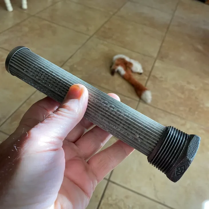 Hand holding a metal pipe with threaded ends