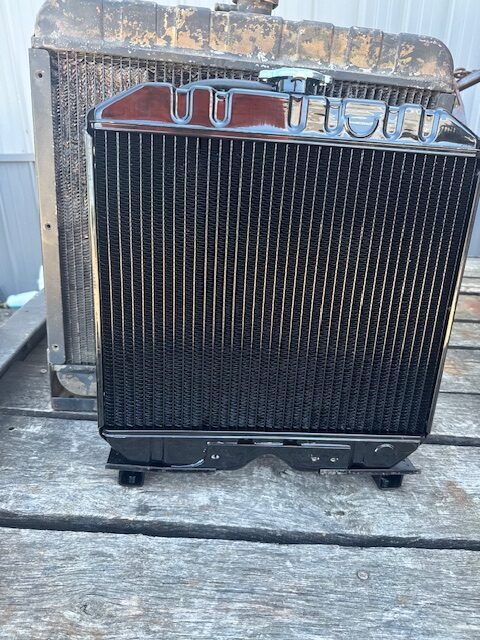 A black car radiator with cooling fins and mounting brackets.