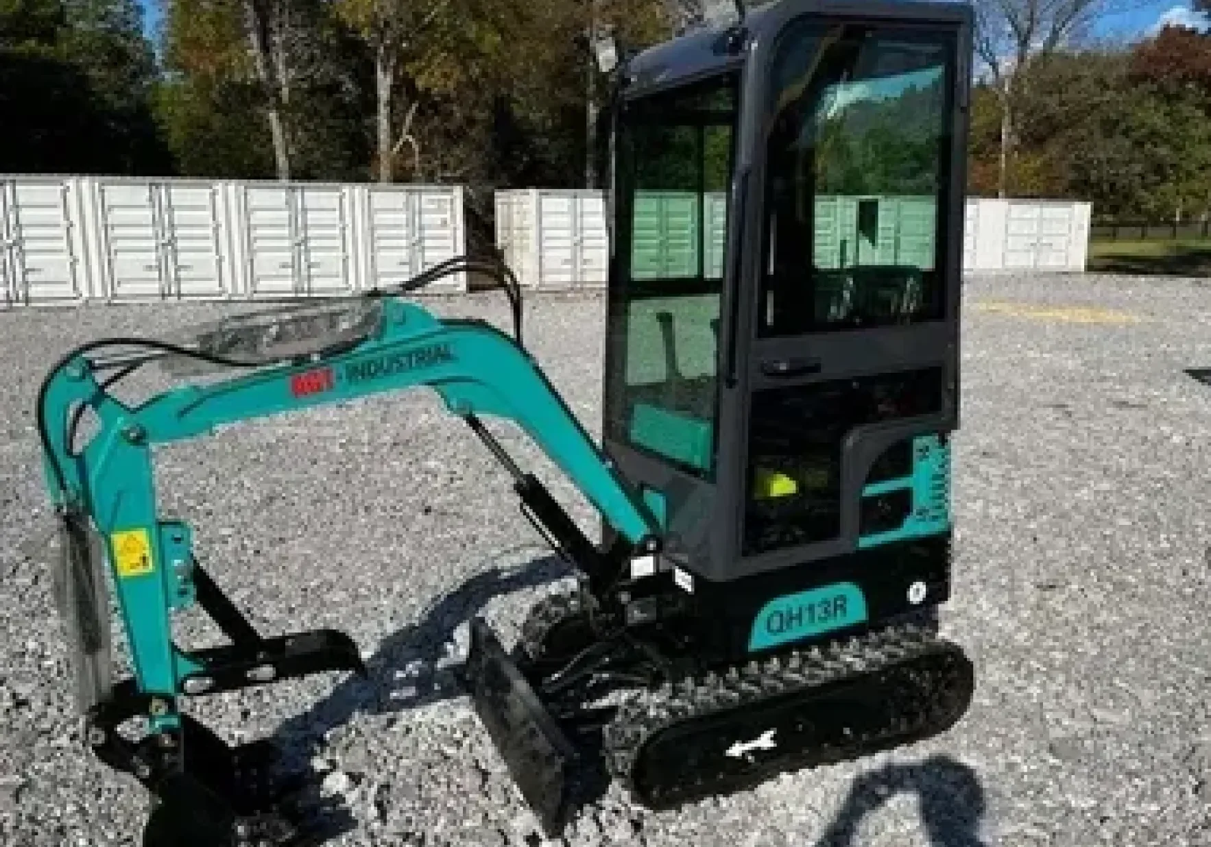 A small green mini excavator parked on gravel outdoors.