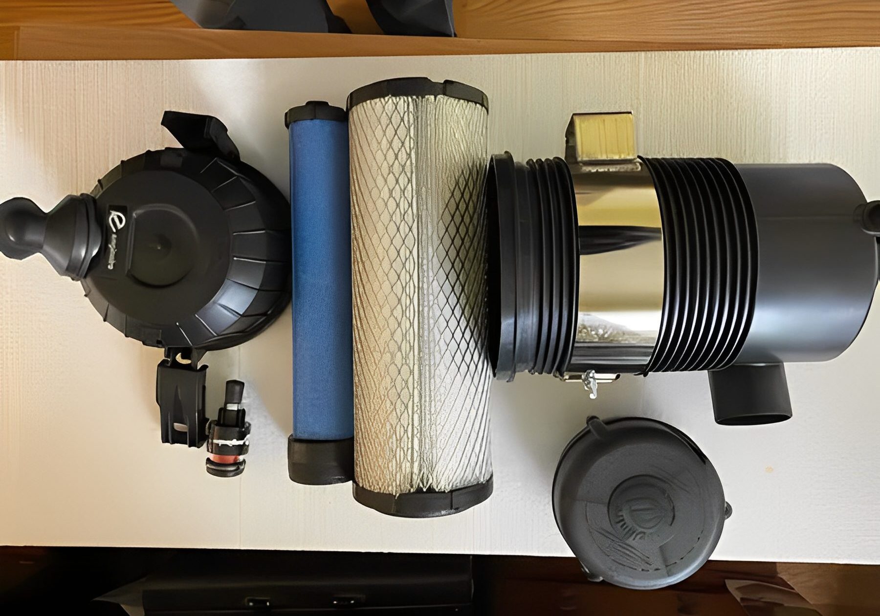 Various mechanical parts including filters and connectors on a wooden surface.